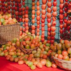 A bold and dramatic photo corner for a 'La Tomatina' themed event, featuring baskets overflowing with ripe tomatoes and curtains made from strings of tomatoes. This is a true feast for the eyes.
