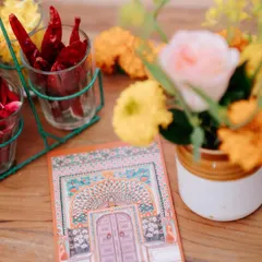 A close-up of the stationery and table decor for the 'Jaipur Wali Haldi'. The invitation card features a beautiful illustration of a Rajasthani door, complemented by fresh marigolds and spices.