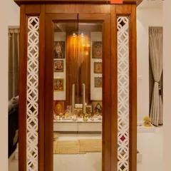 We designed this dedicated pooja room with traditional elements, including ornate white jali work on a wooden frame and glass doors to create a serene and sacred space.