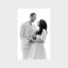 Love at first sight. A classic black and white portrait of a new family, their faces filled with joy and wonder as they hold their newborn. This is a timeless newborn photography moment.