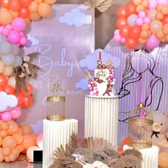 A closer look at our popular 'Baby in Bloom' theme. This setup features a custom backdrop, pampas grass arrangements, themed cake on a fluted pedestal, and a soft, warm color palette of peach and pink balloons.