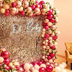 A glamorous 'Oh Baby' shower decoration with a silver sequin wall. The backdrop is framed by a stunning arch of metallic pink and cream balloons.