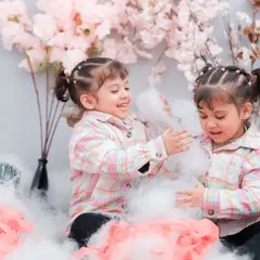Twin girls playing in a sea of soft clouds and flowers. Our themed studio sessions are a magical way to capture your children's imagination.