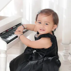 A little pianist at work. This elegant portrait in a black dress at a white piano is a timeless and sophisticated way to capture a milestone.