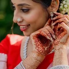 A close-up of a bride adjusting her earring, showcasing her intricate henna and diamond jewelry. We focus on these delicate getting-ready moments that are full of anticipation.