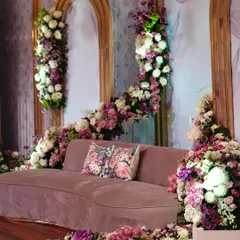 A close-up of a plush, curved sofa surrounded by a sea of purple and white flowers. The floral-print cushion adds a perfect finishing touch to this romantic photo-op.