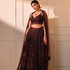 This full-length fashion shot against a clean, paneled wall highlights a stunning sequined lehenga. The simple setup and focused lighting ensure the outfit is the star of the show.