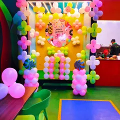 A fun and sweet donut-themed birthday backdrop in a cafe. The colorful balloon arrangement and custom-printed backdrop create a cheerful spot for photos.