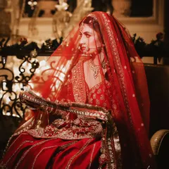 A moment of quiet reflection through the veil. The rich red tones and soft lighting create a classic, romantic bridal portrait that feels both intimate and timeless.