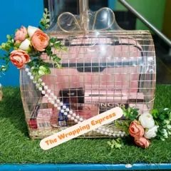 A trousseau gift basket for a bride, elegantly packed in a gold wire frame basket. It includes a vanity case filled with MAC cosmetics and is decorated with flowers.