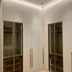 This floor-to-ceiling wardrobe in an Ambala master bedroom combines closed storage with glass-fronted sections. The integrated lighting inside the glass units allows for displaying accessories while keeping them organized.