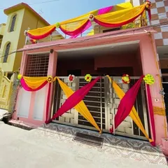 The entrance gate and balcony of a house decorated with bright yellow and pink drapes and floral accents.