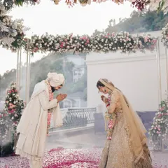 A moment of mutual respect and tradition at a scenic mountain wedding. The couple greets each other under a beautiful floral arch, with the vast hills providing a serene backdrop for their ceremony.