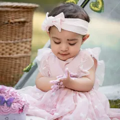 A sweet moment as the birthday girl looks down at her hands covered in pink frosting. These toddler photoshoots are all about capturing their genuine curiosity and delight.