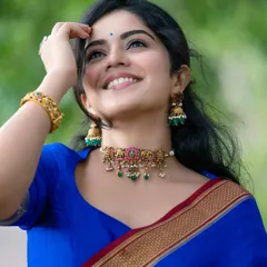 The joy in this image is infectious. The model's upward glance and bright smile, combined with the classic blue saree, create a portrait that feels both candid and beautifully composed.