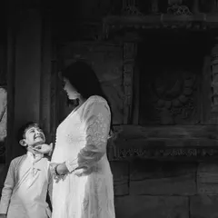 A playful moment between mother and son captured in black and white. The textured stone walls provide a beautiful contrast to their bright outfits.