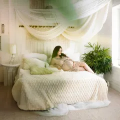 A dreamy and serene lifestyle shot. The mom-to-be relaxes on our beautifully styled studio bed, creating a peaceful and intimate portrait.