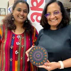 Two friends with their finished dot mandala art. The process of creating these intricate patterns is both relaxing and rewarding.