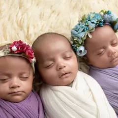 A close-up of the triplet girls, two wearing delicate floral headbands. Posing multiples requires careful coordination to capture them all so serenely.