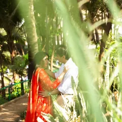 An artistic shot taken through leaves, creating a natural frame around the couple. This technique adds depth and a sense of intimacy, as if we are peeking into a private, romantic moment.