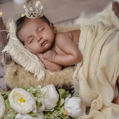 A tiny prince dreaming in his rustic bed. This setup combines a wooden prop bed, soft cream fabrics, and a sprinkle of fairy lights for a touch of magic.