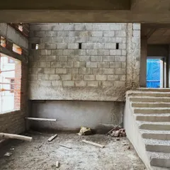 A similar view of the raw interior, highlighting the textures of the concrete and blockwork before finishing is applied.