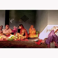 A group of women gathered in prayer. The soft light illuminates the room, creating a quiet, intimate atmosphere. This documentary photograph captures a moment of shared faith and community.