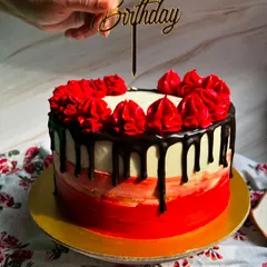 Adding the final touch. A "Happy Birthday" topper is placed on our red and black themed chocolate truffle cake.