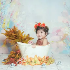 A big, happy smile during a water splash photoshoot. The autumn-themed floral decorations add a beautiful touch of color.