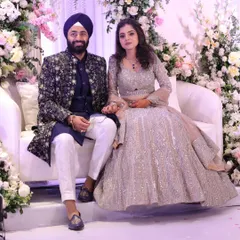 A picture of pure elegance from a client's sangeet night. Seated amidst a beautiful floral backdrop, their coordinated outfits truly stand out. His richly embroidered navy sherwani and her shimmering silver lehenga were designed to be the perfect pair.