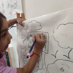 A close-up of a child carefully writing the name of our school on her drawing. This shows the development of fine motor skills and pre-writing abilities through art.