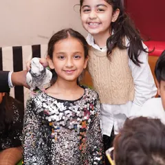 A magician performs a classic trick with a dove, amazing the young party guests.