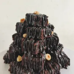A close-up of the Brownie Tower, showing the layers of fudgy brownies drizzled with rich chocolate sauce and topped with crunchy hazelnuts.