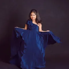 A future fashionista. We love capturing the confidence of older kids, like this girl looking beautiful in her flowing blue gown against a simple background.