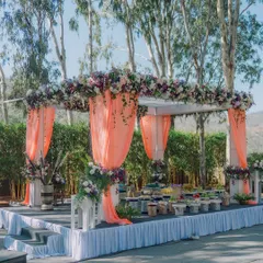 A beautiful food stall setup at an outdoor wedding, draped in peach fabric and adorned with flowers. I believe every part of the wedding, including the catering, should be beautiful.