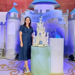 Here I am with the magnificent castle cake, showing the scale and presence it brings to a royal-themed party.