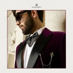 I work with luxurious fabrics to create statement pieces. This close-up highlights the rich texture of a wine-colored velvet tuxedo jacket, complete with a satin lapel and an elegant chain brooch, perfect for festive occasions and black-tie events.