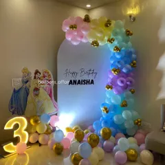 A dreamy Disney Princess theme for a 3rd birthday. This setup includes a pastel rainbow balloon arch, a large light-up number '3', and cutouts of Cinderella, Belle, and Aurora.