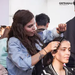 A student focuses on perfecting a hairstyle backstage. This kind of high-pressure environment is the best training for a real-world career.