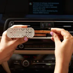 A close-up of our car fragrance vent clip in action. The metallic, minimalist design clips easily onto both vertical and horizontal air vents, discreetly adding a touch of luxury to your car's interior.