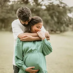A warm, loving embrace from behind. This pose is perfect for outdoor couple maternity shoots, showing connection and support in a natural, beautiful setting.
