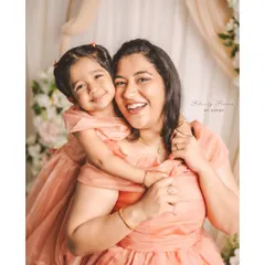 A joyful mother and daughter sharing a heartfelt hug in the studio. This portrait, with its soft floral background, captures the beautiful bond between them, perfect for a Mother's Day or family session.