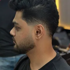 A side profile view showcasing the precision of the temple fade and the crisp line of the beard. Every detail matters when it comes to a sharp men's haircut.