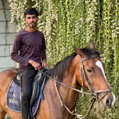 An instructor poses with his horse against a beautiful backdrop of hanging flowers. Our team is passionate about both riding and teaching.