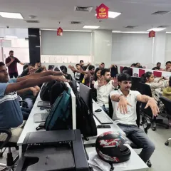 Employees participating in a simple arm and shoulder stretch right at their workstations. These exercises are designed to be quick, effective, and require no change of clothes, making wellness accessible to everyone in the office.