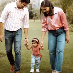 Capturing a toddler's first steps is a precious milestone. Here, we photographed parents gently guiding their child as they walk together during a family session in a park.