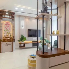 This living room features a modern partition with open shelving, which elegantly separates the space without closing it off. The design also showcases a floating TV unit and a beautiful pooja mandir.
