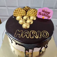 A rich chocolate drip cake for Mario's birthday. This design is topped with golden chocolate decorations for an extra touch of class.