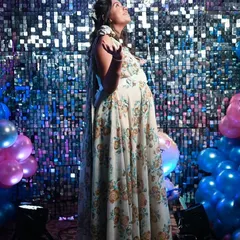 The mother-to-be looks up with a heart full of wonder and anticipation. This portrait captures her joy against the festive "Oh Baby" backdrop, a perfect memory from her special day.