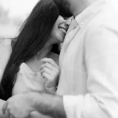 A soft and intimate black and white moment. Her shy smile as she nestles into his embrace is a beautiful, quiet expression of love and trust.